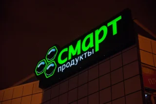 Зелёные световые буквы и знак на тёмной стене